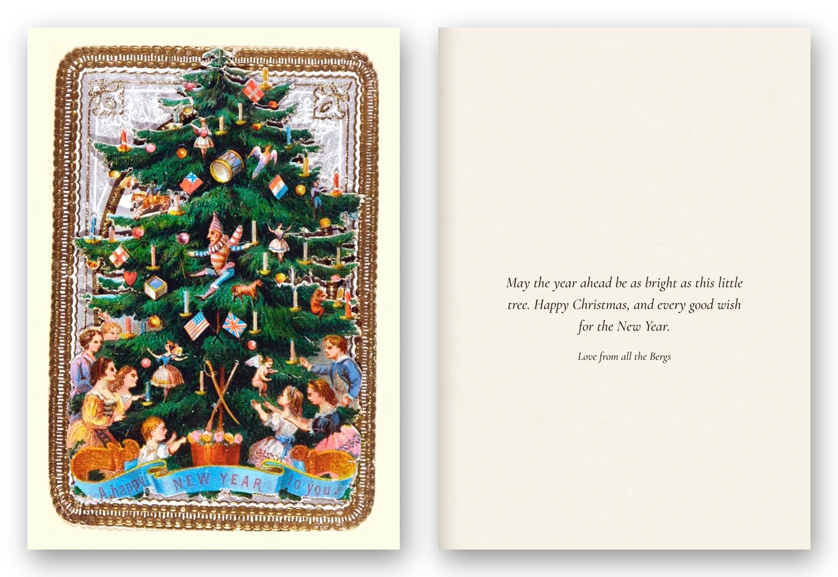 A Victorian card of a Christmas tree hung with flags, toys and candles inside a gilt lace frame, with children at its foot, beside the open card and a New Year message.